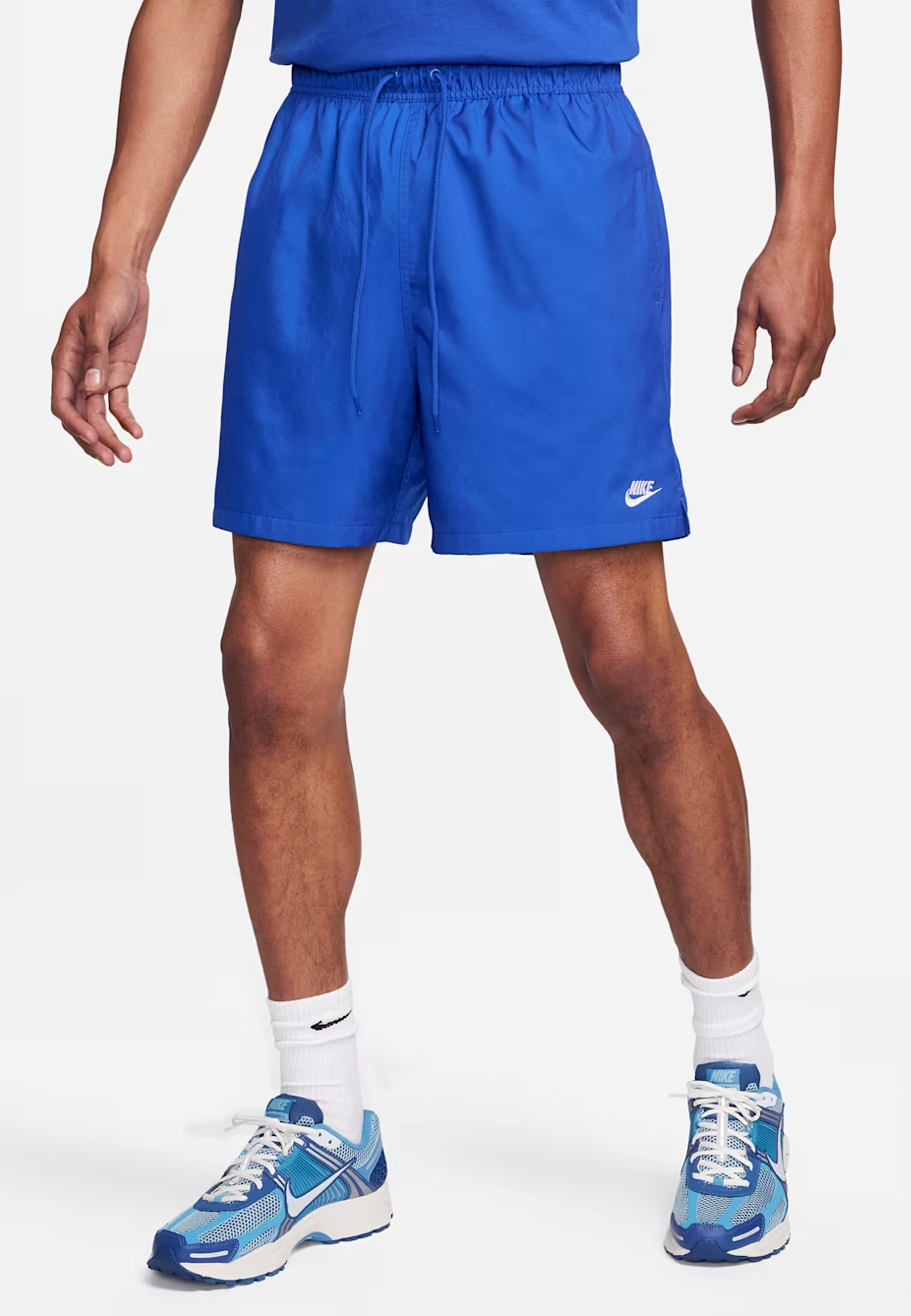 Person wearing blue Nike shorts and shoes on a white background