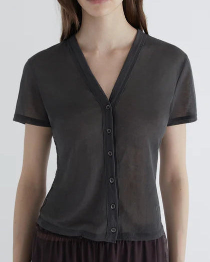 Woman wearing a dark gray cardigan over a black top on a white background